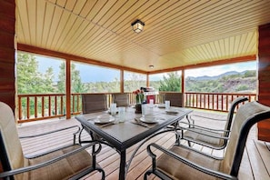 A covered outdoor dining area with a table set for four, surrounded by chairs, and a view of the landscape. - 4BR home - wrap around porch, fire pit & hot tub (New Harmony)