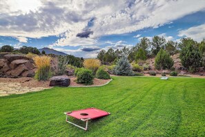 A well-maintained grassy area with a red disc golf basket, surrounded by rocks and various shrubs. - 4BR home - wrap around porch, fire pit & hot tub (New Harmony)