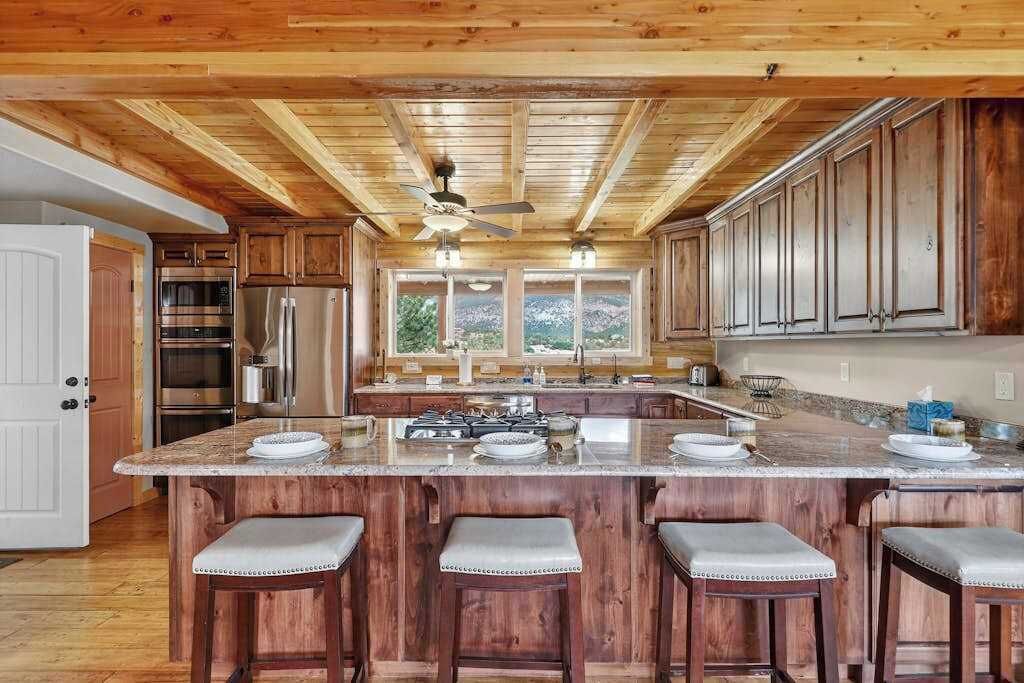 A kitchen with wooden cabinets, a central island with bar stools, and a ceiling fan.