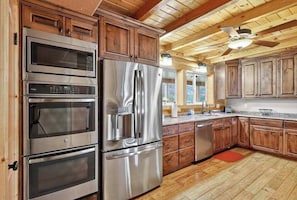 A kitchen with built-in appliances, wooden cabinets, and a ceiling fan. - 4BR home - wrap around porch, fire pit & hot tub (New Harmony)