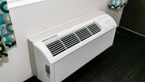 A white wall-mounted air conditioner with a control panel and a vent grille. - Executive Family Suite (Anaheim)