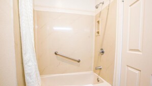 A bathroom with a bathtub, a shower, and a door. - Executive Family Suite (Anaheim)