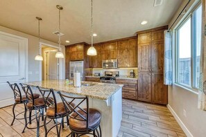 A kitchen with wooden cabinets, a granite countertop, and a bar area with stools. - Spacious 5BR Mountainview Paradise Village (Santa Clara)