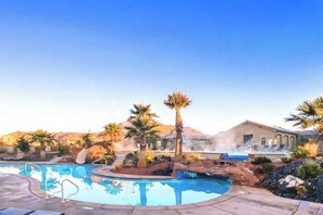 A pool area with a hot tub, palm trees, and a building in the background. - Spacious 5BR Mountainview Paradise Village (Santa Clara)