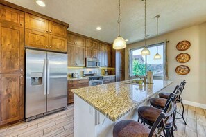 A kitchen with wooden cabinets, stainless steel appliances, a granite countertop, and a bar area with stools. - Spacious 5BR Mountainview Paradise Village (Santa Clara)
