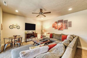 A living room with a sofa, a coffee table, a TV, and a ceiling fan. - Spacious 5BR Mountainview Paradise Village (Santa Clara)