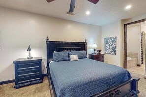 Ein Schlafzimmer mit einem großen Bett, einem Schminktisch, einem Nachttisch und einem Bild an der Wand.