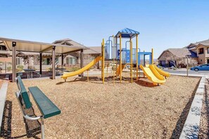 A playground with slides and a climbing structure, surrounded by a covered seating area and a bench. - 4BR mtn-view townhome with pools, hot tubs, gym (Washington)