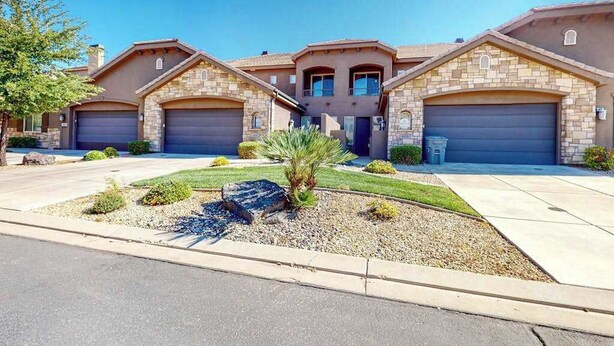 A residential building with a stone facade, two garages, and a landscaped front yard with a palm tree. - 4BR mtn-view townhome with pools, hot tubs, gym (Washington)