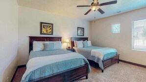 A bedroom with two beds, a ceiling fan, and framed artwork on the walls. - 4BR mtn-view townhome with pools, hot tubs, gym (Washington)