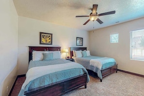 A bedroom with two beds, a ceiling fan, and framed artwork on the walls. - 4BR mtn-view townhome with pools, hot tubs, gym (Washington)