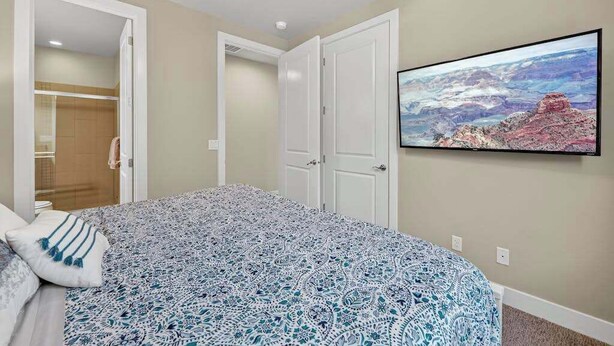 A bedroom with a bed, a ceiling fan, a door, and a wall-mounted TV displaying a landscape. - 5BR home with waterpark, private pool and spa (Santa Clara)