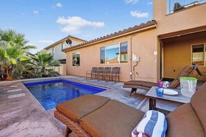 Un jardin à l’arrière d’une maison, avec une piscine, du mobilier d’extérieur et un espace patio.