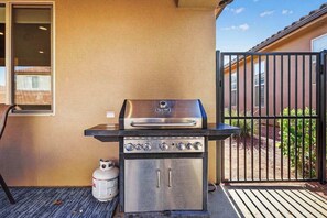 Un barbecue au gaz portable, doté d’une finition en acier inoxydable, d’une bouteille de gaz et d’un couvercle noir.