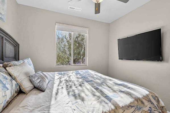 A bedroom with a bed, pillows, a window, and a flat-screen TV mounted on the wall. - 5BR home with waterpark, private pool and spa (Santa Clara)