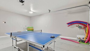 A ping pong table with a ball and paddle, a green exercise ball, and colorful exercise equipment in a room with white walls and a ceiling-mounted projector. - 5BR home with waterpark, private pool and spa (Santa Clara)