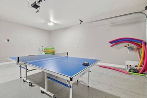 A ping pong table with a ball and paddle, a green exercise ball, and colorful exercise equipment in a room with white walls and a ceiling-mounted projector. - 5BR home with waterpark, private pool and spa (Santa Clara)