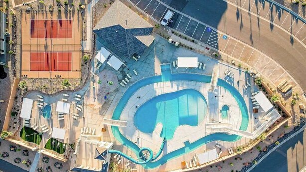 An aerial view of a resort with a large swimming pool, tennis courts, and a parking area. - 5BR shared pool with slide near outdoors (Washington)