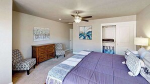 A bedroom with a bed, a ceiling fan, a dresser, two chairs, and artwork on the walls. - 5BR shared pool with slide near outdoors (Washington)