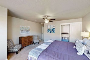 A bedroom with a bed, a ceiling fan, a dresser, two chairs, and artwork on the walls. - 5BR shared pool with slide near outdoors (Washington)