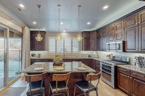 A kitchen with a central island, dark wooden cabinets, stainless steel appliances, and pendant lighting. - 5 BR home with hot tub & water park PV90 (Santa Clara)