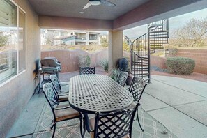 An outdoor patio with a round table and chairs, a grill, and a spiral staircase leading to an upper level. - 5 BR home with hot tub & water park PV90 (Santa Clara)