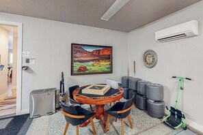 A room with a round wooden table, black chairs, a painting of a landscape, an air conditioning unit, a clock, and exercise balls. - 5 BR home with hot tub & water park PV90 (Santa Clara)