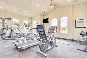 A gym with cardio machines, weight benches, and a TV on the wall. - 5 BR home with hot tub & water park PV90 (Santa Clara)