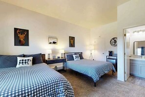 Une chambre d’hôtel avec deux lits, un bureau, une chaise, une lampe et une horloge au mur.