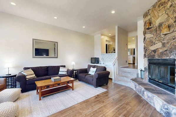 A living room with a fireplace, a sofa, a coffee table, and a television.
