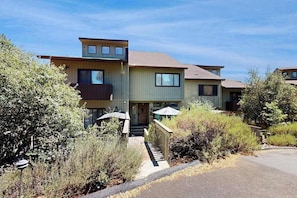 A multi-story residential building with a front entrance, a small porch, and a staircase leading to the entrance.