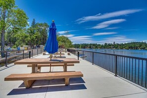 A riverside walkway with picnic tables and a blue umbrella.