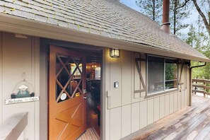 A cabin with a wooden door, a welcome sign, and a window with a view of the outdoors.