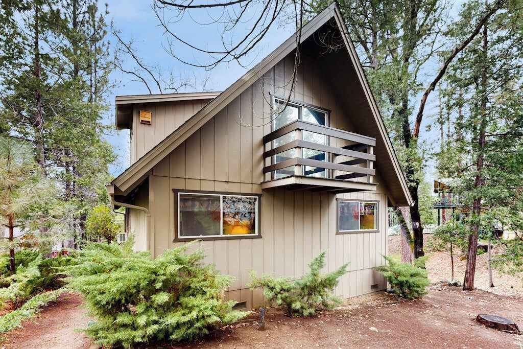 Una casa moderna con techo inclinado, un balcón y un pequeño porche.