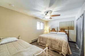 A bedroom with two beds, a ceiling fan, a window, and a mirror. - Tamarack Dream - Tamarack Estates (Lakeshore)