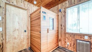 Eine Holzhütte mit Sauna, einem Fenster mit Jalousien und einer Tür.