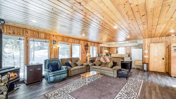 Ein gemütliches Blockhaus-Interieur mit Kamin, zwei Sofas, einem Couchtisch und einer Küchenzeile.