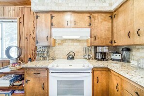 A kitchen with wooden cabinets, a white stove, and various appliances. - Tamarack Dream - Tamarack Estates (Lakeshore)