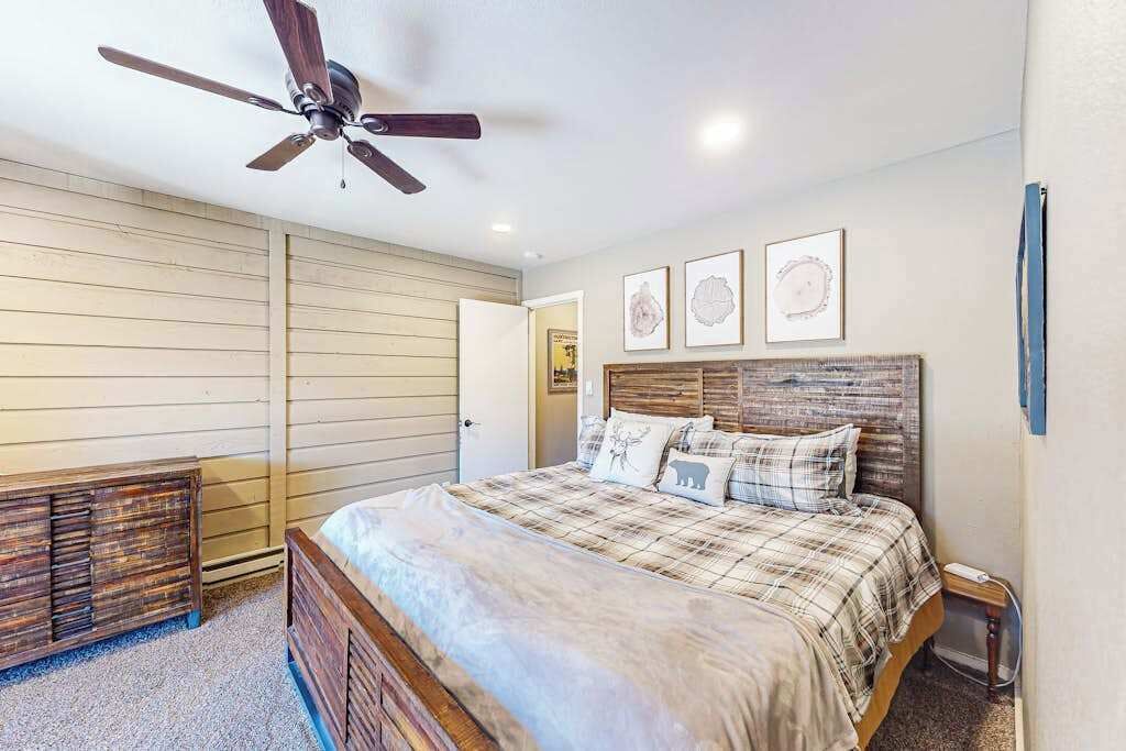 Un dormitorio con cama, ventilador de techo y obras de arte en la pared.