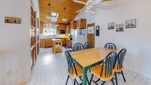 A spacious kitchen with wooden cabinets, a dining table with chairs, and a ceiling fan. - Escape to Yosemite - Pine Mountain Lake (Groveland)