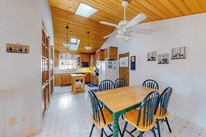 Eine geräumige Küche mit Holzausstattung, einem Esstisch mit Stühlen und einem Deckenventilator.
