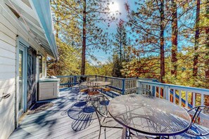 A covered outdoor deck with a table and chairs, surrounded by trees. - Escape to Yosemite - Pine Mountain Lake (Groveland)