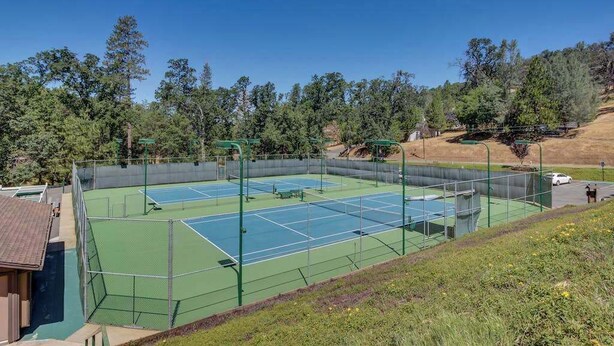 An outdoor tennis court with a net, surrounded by a fence, and trees in the background. - Escape to Yosemite - Pine Mountain Lake (Groveland)