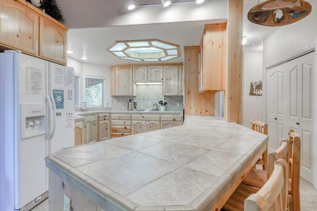 A kitchen with a large island, white cabinets, and a hexagonal skylight.