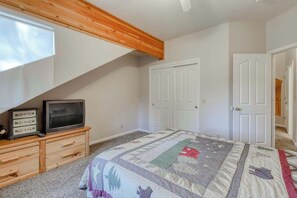 A bedroom with a bed, a TV on a wooden dresser, a quilt, and white doors. - Hatcher's Hideaway - Ockenden Ranch (Shaver Lake)