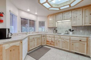 A kitchen with wooden cabinets, a built-in oven, and a window with blinds. - Hatcher's Hideaway - Ockenden Ranch (Shaver Lake)