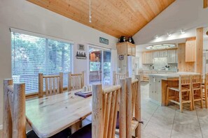 A spacious kitchen with wooden cabinets, a central island, and a dining area with wooden chairs. - Hatcher's Hideaway - Ockenden Ranch (Shaver Lake)
