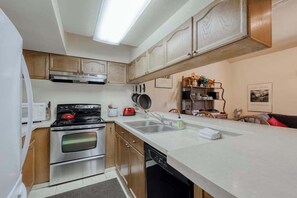 Una cocina compacta con estufa, horno, microondas y lavaplatos.