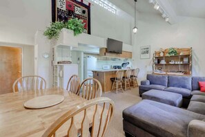 A modern living space with a dining area, kitchen, and seating area.