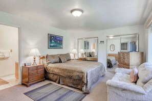 Un dormitorio con cama, cómoda, espejo y una silla.